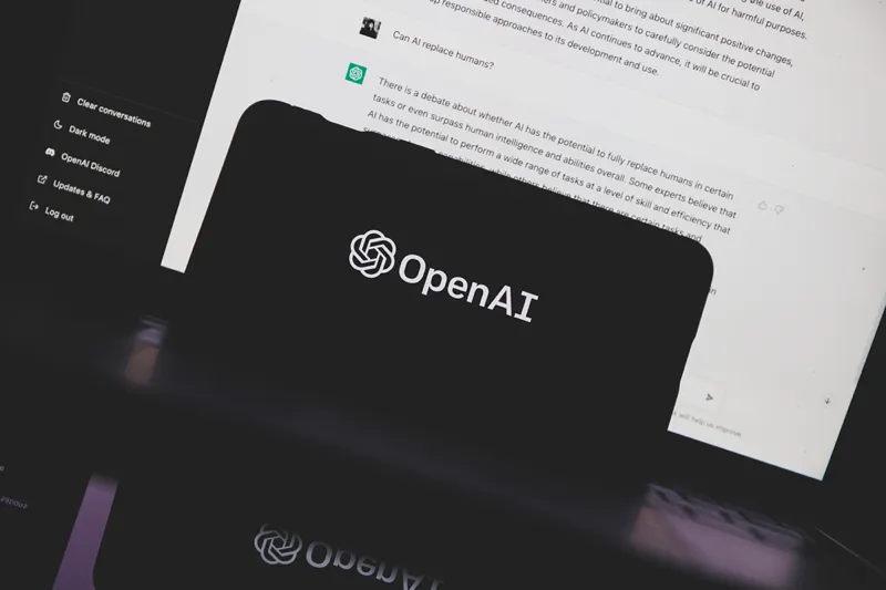گوشی هوشمندی که آرم OpenAI را با رابط چت در پس‌زمینه نمایش می‌دهد.