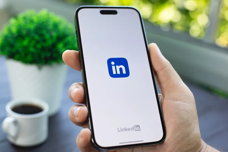 رابط برنامه LinkedIn که هوش مصنوعی را در رسانه های اجتماعی برای شبکه های حرفه ای به نمایش می گذارد. لوگوی لینکدین در گوشی هوشمند نمایش داده می شود.