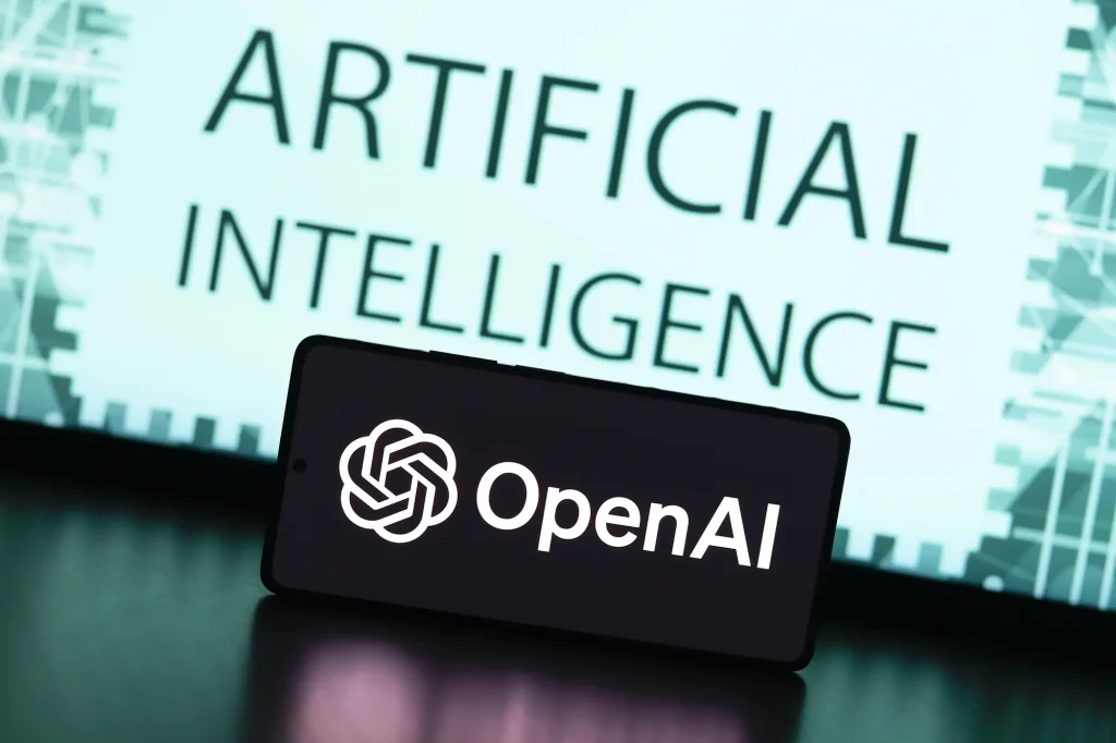تلفن هوشمند که آرم OpenAi را در مقابل صفحه نمایش با کلمات نشان می دهد "هوش مصنوعی ،" نمایندگی برند ورود به سیستم OpenAI.